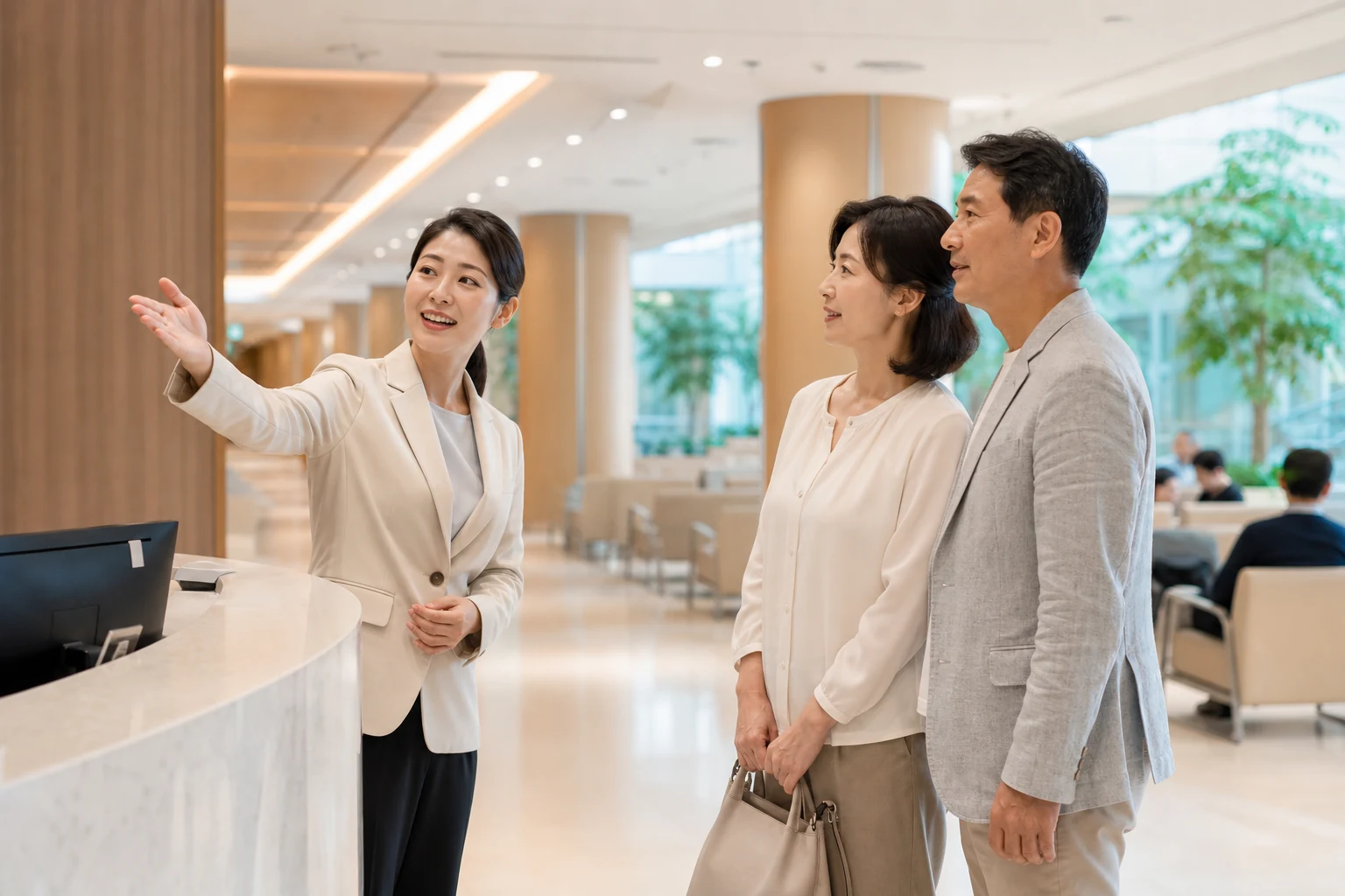 밝은 조명 아래 병원 실내에서 안내 데스크 직원이 방문객에게 접수와 진료과 위치를 설명하는 장면